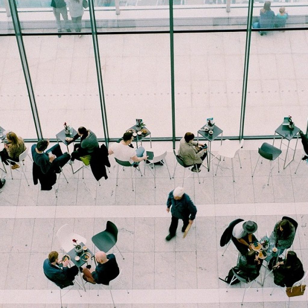 A row of people sat at different cafe tables shot from a bird's eye view