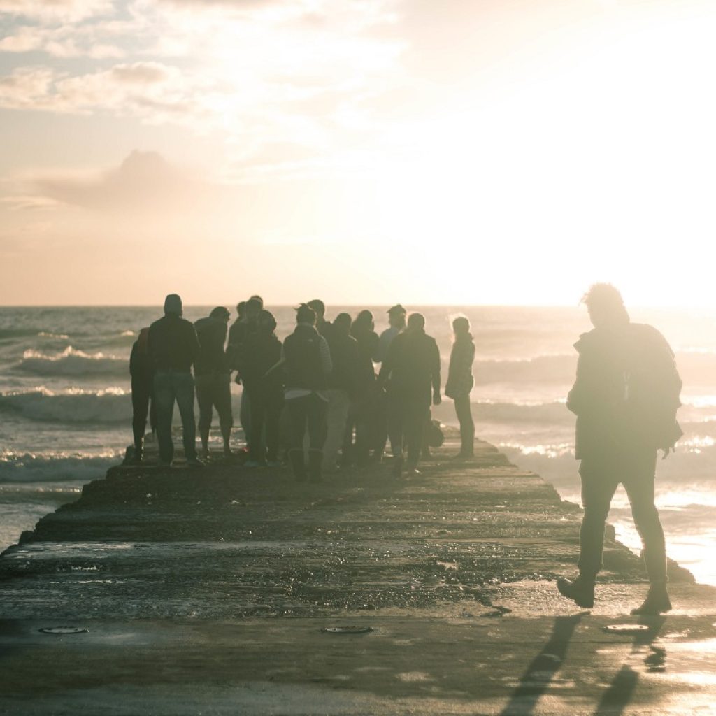 A group of people gathered at the end of a boardwalk on the coast