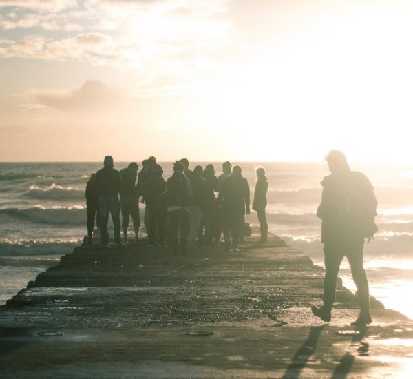 A group of people gathered at the end of a boardwalk on the coast