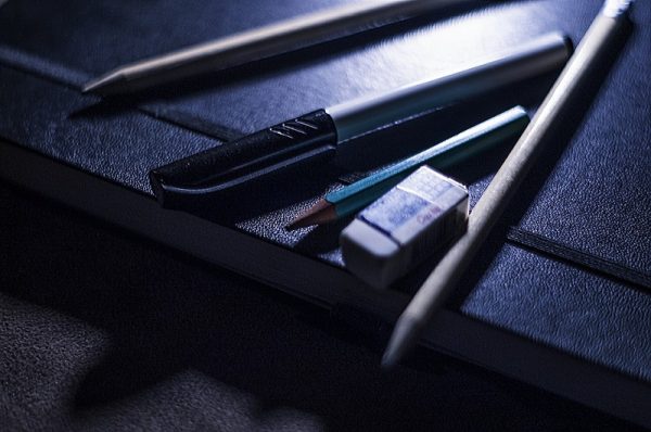 A pen, pencils and rubber on top of a black leather-bound notebook