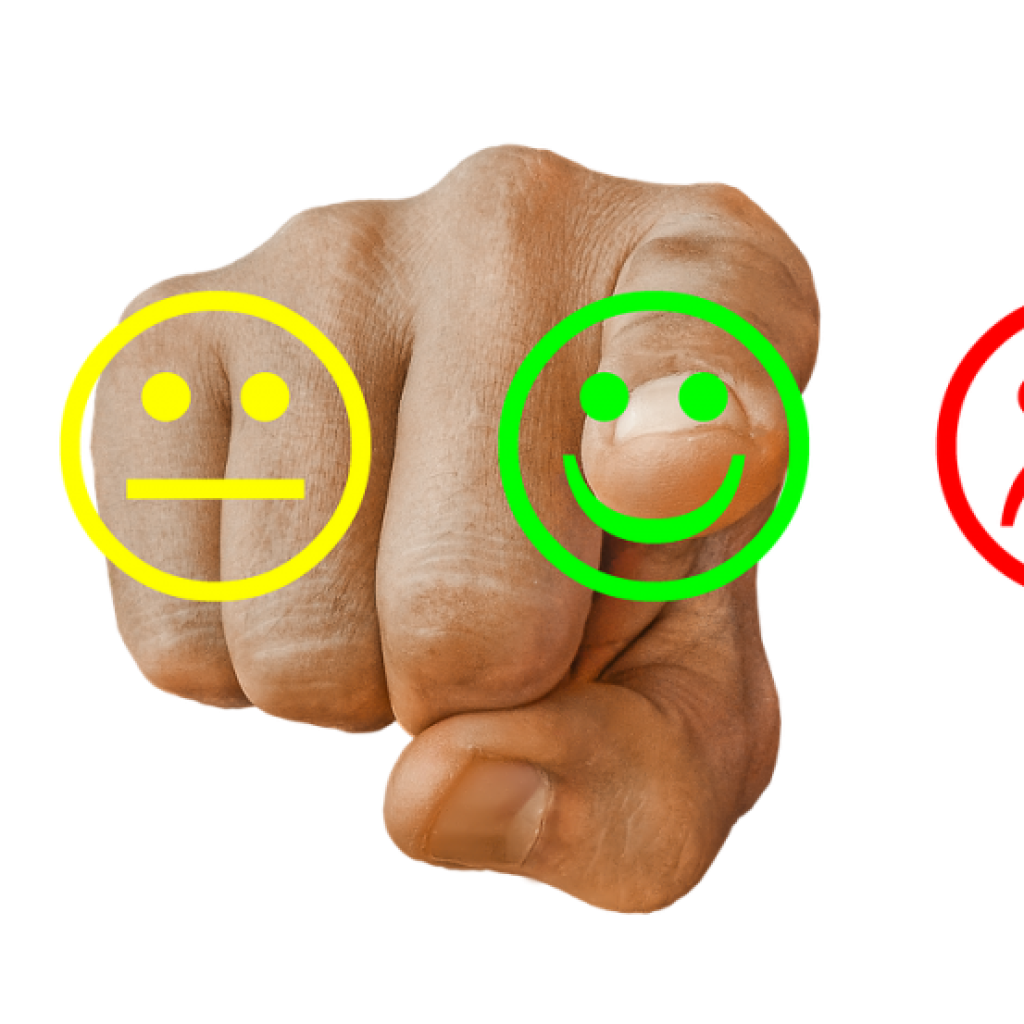 A hand pointing at a three way review system containing three differently coloured icon options, neutral positive and negative