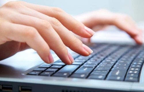 A pair of hands typing on a black laptop keyboard