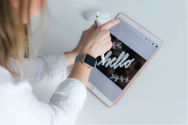 Woman in a white shirt creating a typography graphic using a tablet and apple pencil