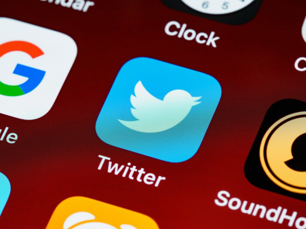 Twitter App logo displayed on a handheld device with a red background