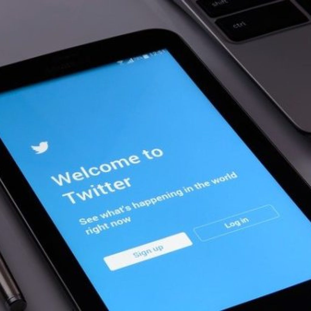 Tablet laying on a table displaying a blue Welcome to Twitter Login Page