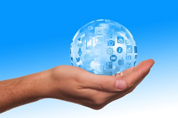 Cupped hand holding out a transparent sphere with social platform logos on a blue background