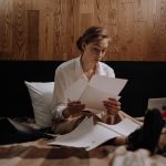 Woman looking through paperwork on a bed
