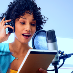 Woman using a microphone to record a podcast while reading a notebook