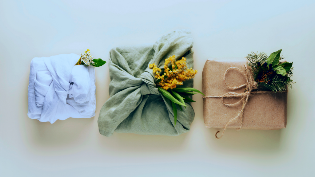 three gifts wrapped in eco friendly wrappping, with flower decorations on a light background