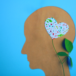 blue background with a paper cut out of a side profile with a heart shaped flower over the temple.