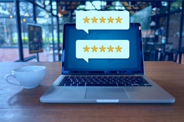 Laptop computer with two speech bubbles emitted from the screen displaying five star reviews