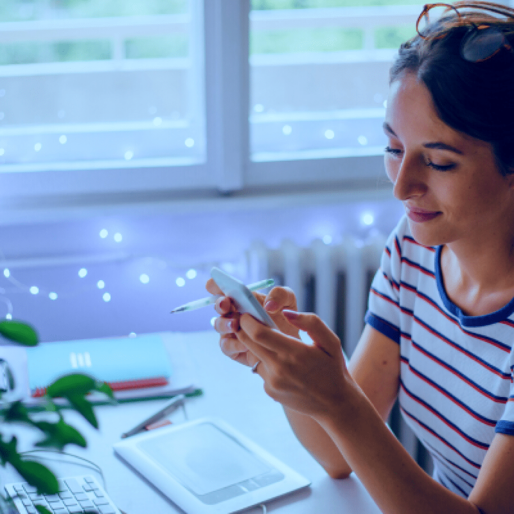 A woman sitting at a desk using her mobile phone