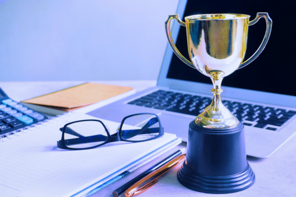 A trophy placed on an office desk next to an open laptop and documents