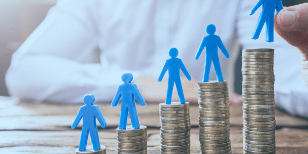 A person sat at a desk with a stack of coins with blue people standing on top of them